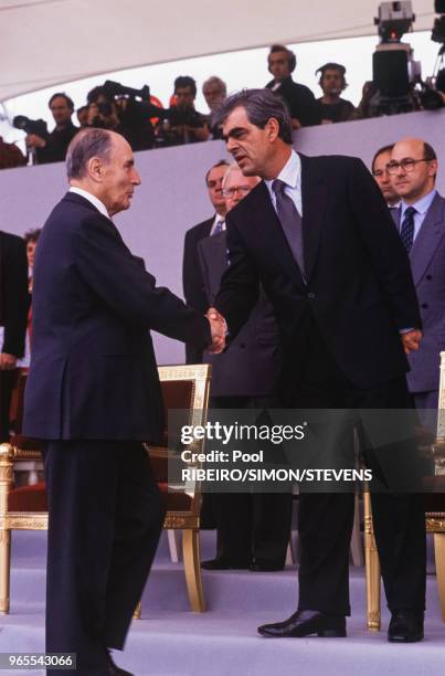 Le président François Mitterrand sur la tribune officielle serre la main de Henri Emmanuelli le 14 juillet 1992 à Paris, France.