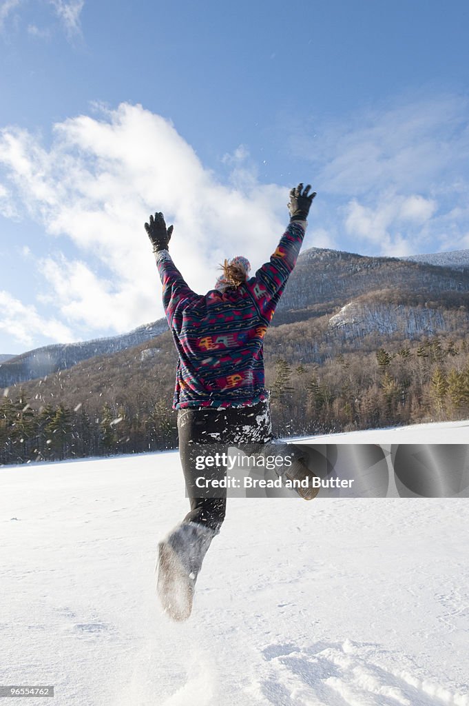 Young woman jumping in the snow