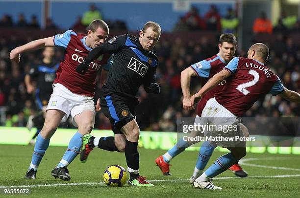 Wayne Rooney of Manchester United clashes with Richard Dunne and Luke Young of Aston Villa during the FA Barclays Premier League match between Aston...