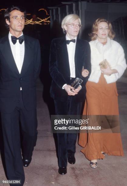 Artiste Andy Warhol, au centre, arrive à une soirée le 25 février 1974 à Monaco.