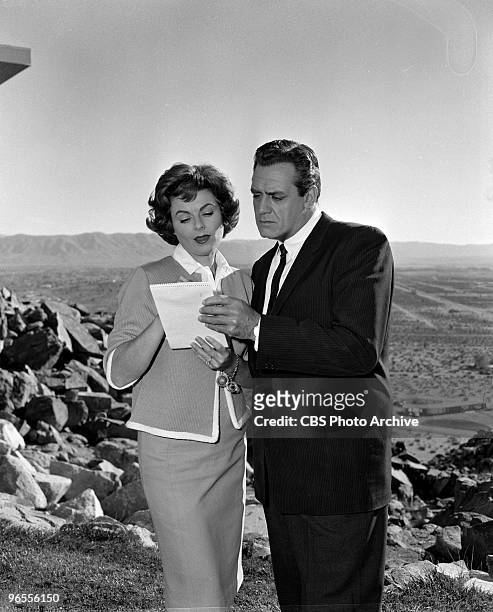 Actor Raymond Burr as Perry Mason examines a piece of paper with actress Barbara Hale as Della Street in an episode of the TV series "Perry Mason"...