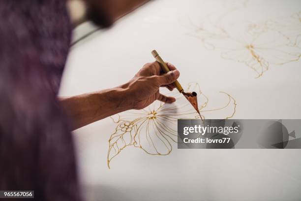 asiatischen mann arbeitet in batik workshop - traditioneller batikstil stock-fotos und bilder