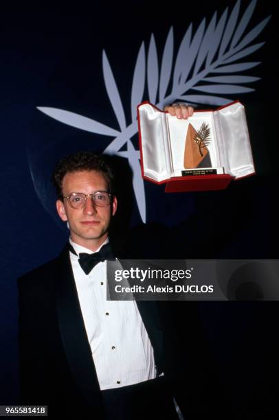 Le metteur en scène Steven Soderbergh montre la Palme d'Or qu'il vient de recevoir lors de la soirée de clôture du Festival de Cannes le 23 mai 1989,...