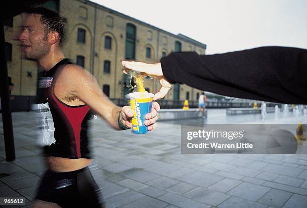 Competitors receive Lucozade Sport at a feeding station during the 2001 London Triathlon held at the Royal Victoria Docks in London. \ Mandatory...