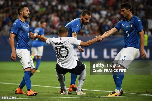 France's foward Kylian Mbappe is helped up by Italy's players during the friendly football match between France and Italy at the Allianz Riviera...