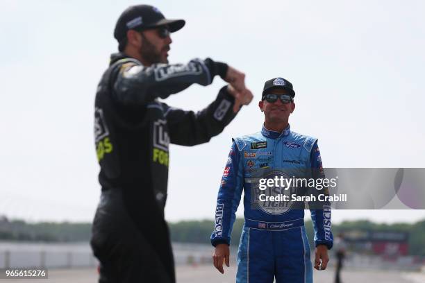 Clint Bowyer, driver of the Busch Light Ford, and Jimmie Johnson, driver of the Lowe's for Pros Chevrolet, stand on the grid during qualifying for...