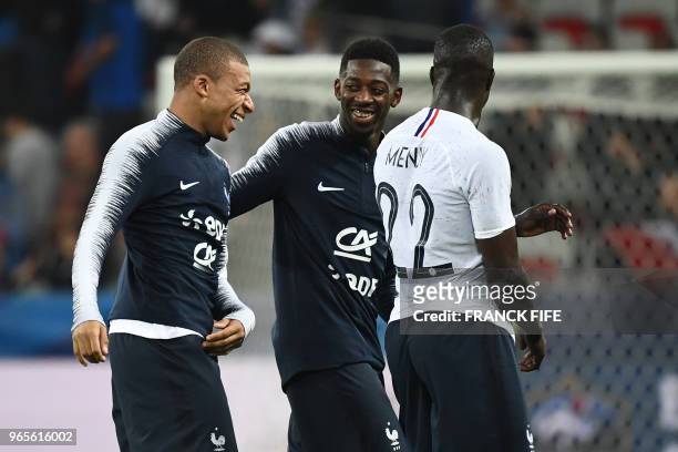 France's foward Kylian Mbappe celebrates with France's foward Ousmane Dembele and France's midfielder Benjamin Mendy after winning the friendly...