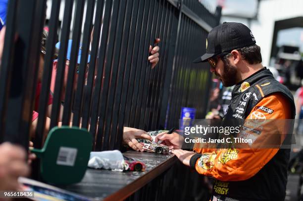 Martin Truex Jr., driver of the Bass Pro Shops/5-hour ENERGY Toyota, signs autographs during qualifying for the Monster Energy NASCAR Cup Series...
