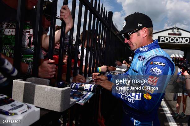 Clint Bowyer, driver of the Busch Light Ford, signs autographs after qualifying for the Monster Energy NASCAR Cup Series Pocono 400 at Pocono Raceway...