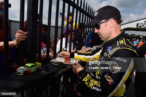 Matt Kenseth, driver of the Ford Ford, signs autographs during qualifying for the Monster Energy NASCAR Cup Series Pocono 400 at Pocono Raceway on...