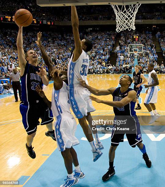 Duke guard Jon Scheyer shoots around North Carolina forward John Henson during a men's college basketball game at Dean Smith Center on February 10,...