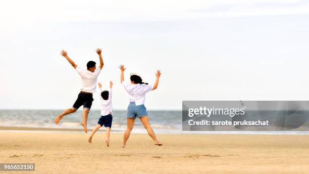 happy asian family of father, mother and sun jumping and relaxing on the beach . holiday family ,insurance concept . - happy jumping stockfoto's en -beelden