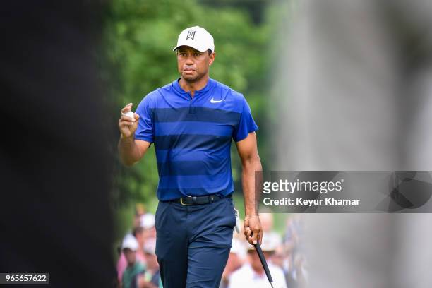 Tiger Woods celebrates and waves his ball to fans after making a birdie putt on the ninth hole green during the second round of the Memorial...