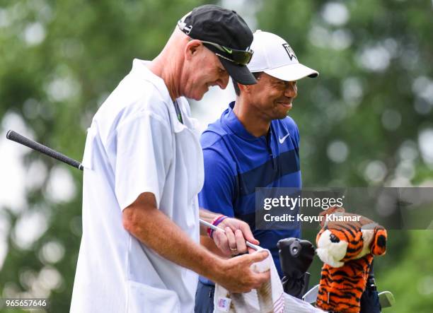 Tiger Woods smiles with his caddie Joe LaCava after hitting his tee shot to six feet on the 12th hole during the second round of the Memorial...