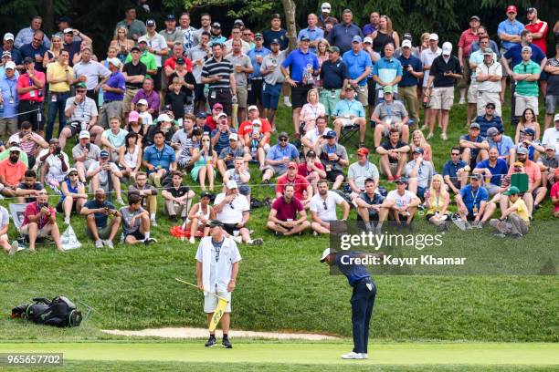 Tiger Woods stretches his back after a rain delay as fans watch on the 12th hole green during the second round of the Memorial Tournament presented...