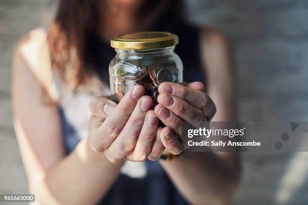 woman holding a jar of money - copper bracelets stock-fotos und bilder