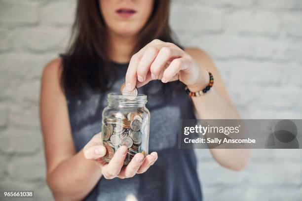 woman holding a jar of money - money jar stock-fotos und bilder