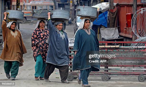 Kashmiri women carry metal containers as they walk along a steet during a undeclared curfew in Srinagar on February 11, 2010. A security lockdown and...
