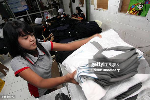 Worker stacks a pile of finished shirts at the PT Caladi Lima Sembilan garment factory in Bandung, West Java, Indonesia, on Wednesday, Feb. 10, 2010....