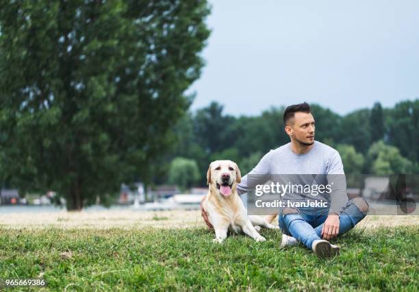 handsome man sitting with his dog outdoors - ivanjekic stock pictures, royalty-free photos & images