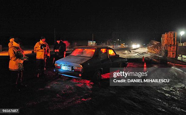 Romanian customs officer stops a car before searching it for smuggled products, like cigarettes and alcohol, on the road to the city of Iasi, 400 kms...