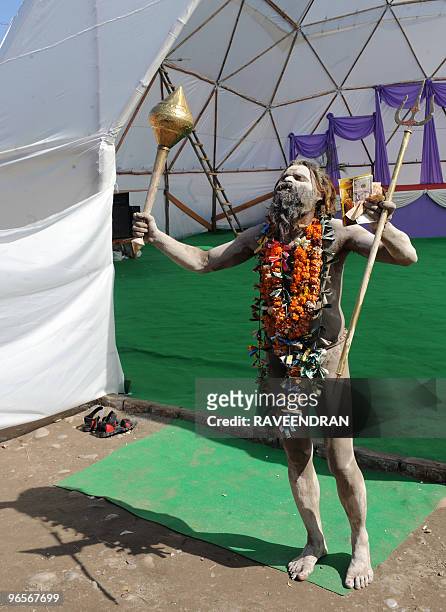 An Indian Sadhu holds a mace and a fistful of US dollars and Indian Rupees at Haridwar on February 11 on the eve of the first Royal Bath Sahi Snan of...