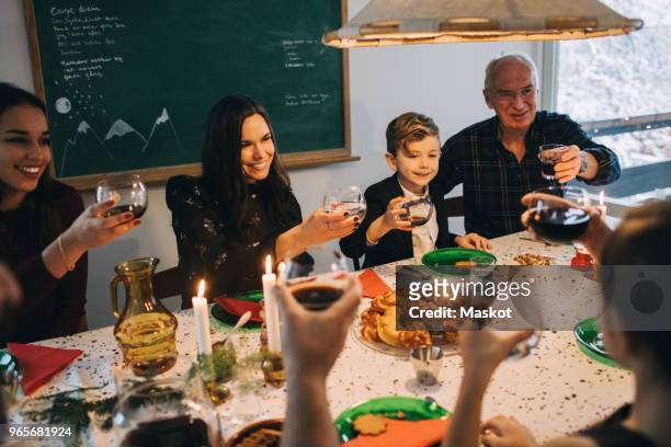 family toasting drinks while enjoying meal at table during christmas - national day in sweden 2017 stockfoto's en -beelden