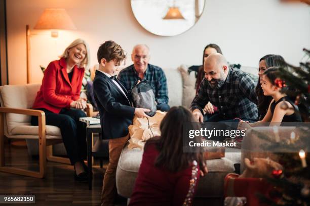 boy showing christmas presents to multi-generation family at living room - national day in sweden 2017 stock pictures, royalty-free photos & images