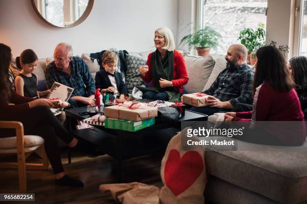 boy showing christmas presents to multi-generation family at living room - grandmas living room stock-fotos und bilder