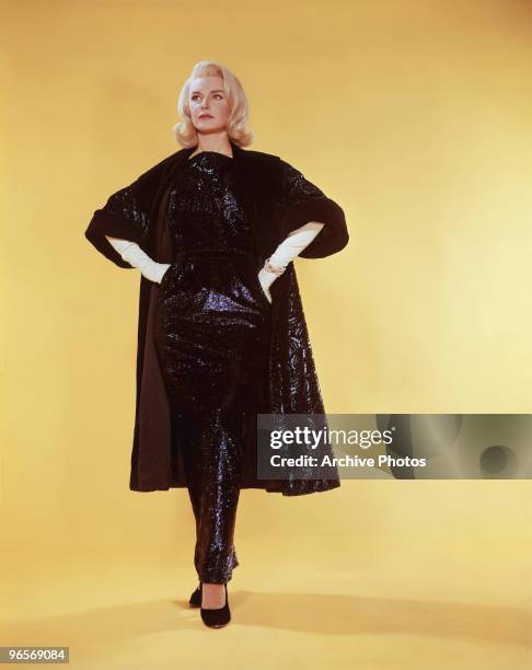 American actress Joanne Woodward in a black sheath dress and matching coat, circa 1965.