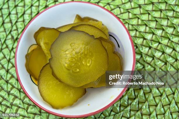 cucumber pickles served on a white small bowl and over a green textured background - cetriolino foto e immagini stock
