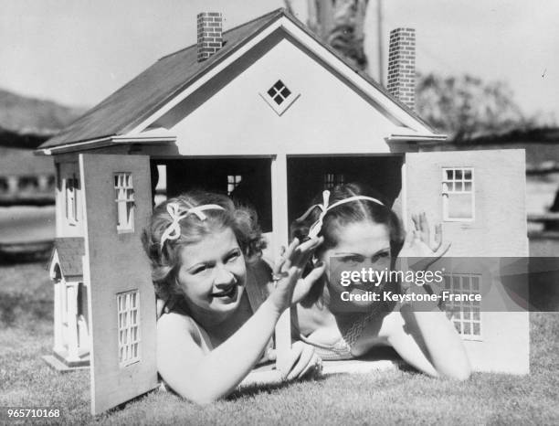 Des soeurs jumelles posant dans une maison miniature, aux Etats-Unis le 16 mars 1934.