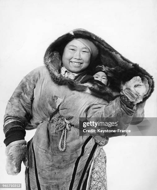 Femme esquimau portant son enfant dans le dos enveloppé dans une peau de caribou, en Alaska, Etats-Unis le 15 mars 1947.