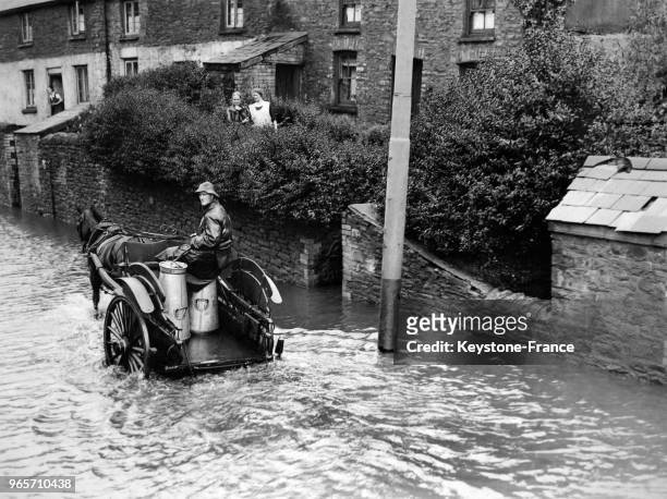 Un laitier assis dans sa charrette tirée par son cheval a bien du mal à progresser dans les rues inondées d'un village gallois après la crue de deux...