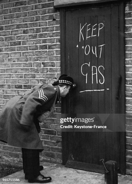 Un étudiant du collège militaire de musique de Twickenham regarde à tavers le trou de la serrure d'une porte condamnée où il est écrit à la craie...