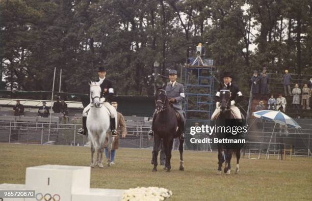 Winners of the Equestrian Grand Prix de Dressage approach the victory stand. Center, Henry Chammartin, Switzerland, left, Harry Boldt of Germany,...