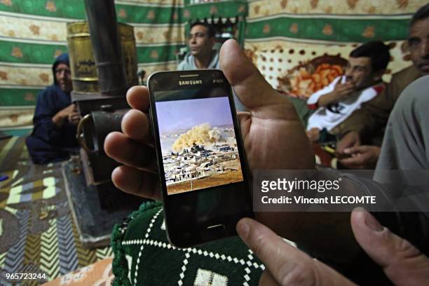 Un réfugié syrien montre sur son téléphone portable la photographie d'une frappe de l'aviation syrienne observée depuis son balcon à Alep, dans un...