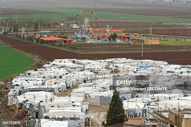 Vue d?ensemble d'un camp informel de réfugiés, installé entre des champs, et constitué d?une centaine de tentes recouvertes de bâches blanches...