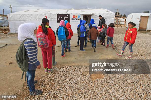 Enfants s'apprêtant à entrer dans une tente école pour y suivre un programme d'alphabétisation dans un camp de réfugiés syriens en Syrie, le 22...