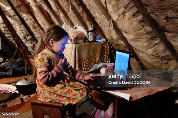Dans le tchoum, fillette regardant un film sur l'ordinateur familial, 19 avril 2017, Péninsule de Yamal, Sibérie, Russie.