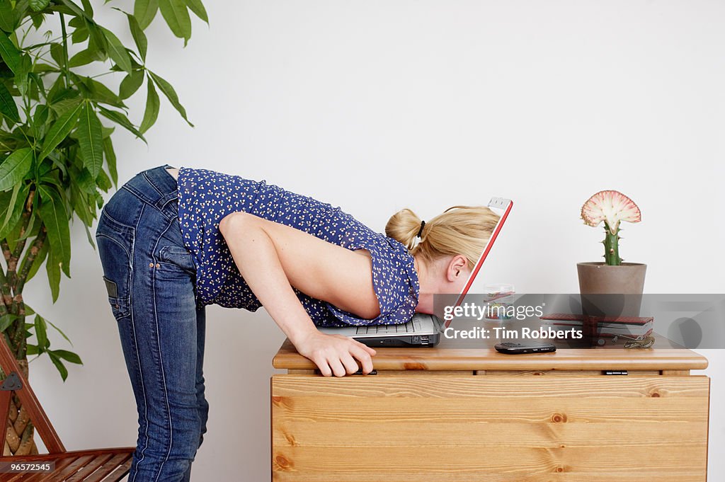 Young woman peering inside laptop screen