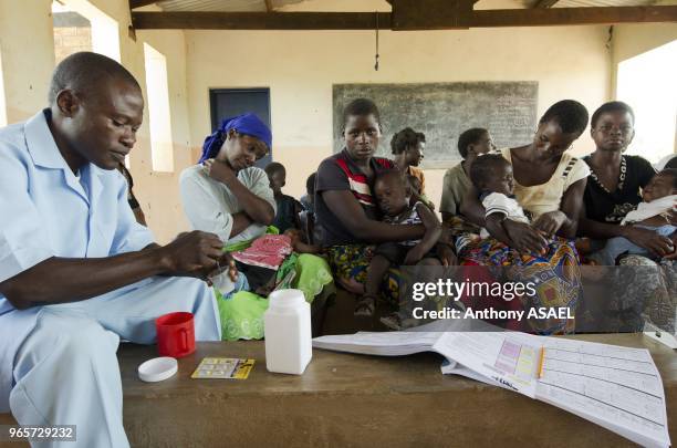 Malawi, Northern Region, Rumphi, Health Surveillance Assistant Bruno Banda checks the breathing rate of 2 year old Grace NKhoma who is diagnosed with...