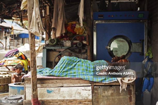 India, Maharashtra, Mumbai, man sleeping in front of washing machine in Dhobi Ghat, world's biggest open air laundromat.