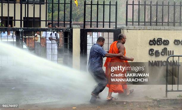 Demonstrator and monk are hit by water cannon spray during a protest in the eastern Colombo suburb of Maharagama on February 11, 2010. Sri Lankan...