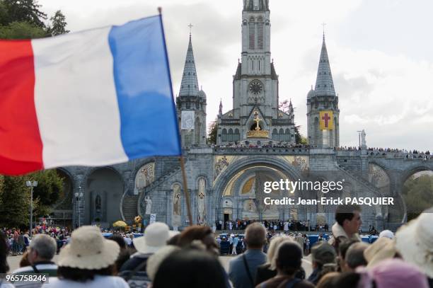 French pilgrims holding a French flag with the Basilica of the Immaculate Conception in the background pictured in Lourdes, France on August 13, 2010.