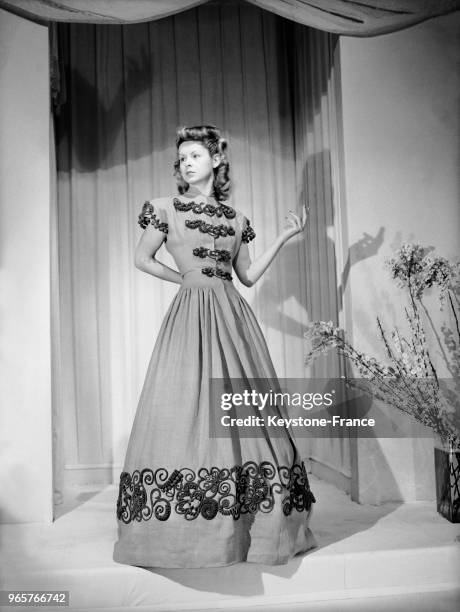 Mannequin présentant une robe du soir de Maggy Rouff en toile capucine brodée de laine verte et violette, le 20 février 1947.