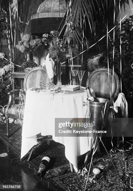 Présentation d'une table en fin de fête de réveillon de Noël avec des confettis et des serpentins, le 24 décembre 1934.