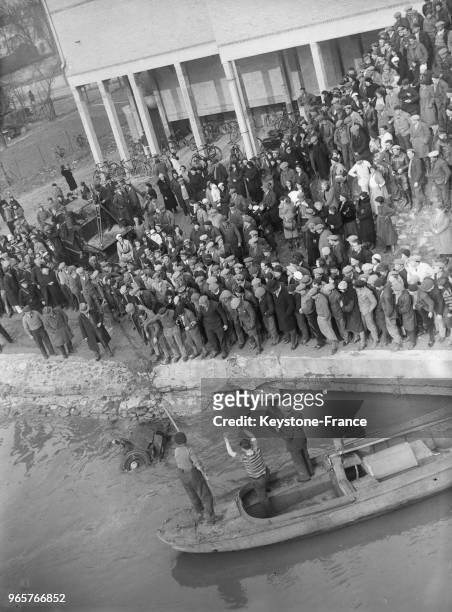 La foule assiste au repêchage de la voiture de l'ingénieur parisien qui s'est suicidé en se jetant avec son automobile du pont de Créteil, France le...