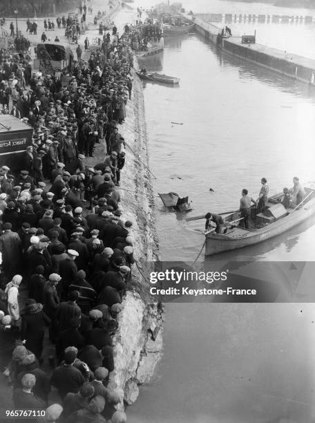 La foule assiste au repêchage de la voiture de l'ingénieur parisien qui s'est suicidé en se jetant avec son automobile du pont de Créteil, France le...