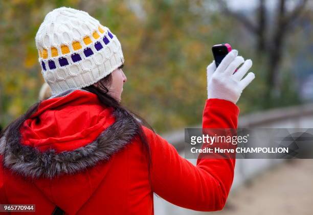 Jeune femme prenant une photo avec son téléphone, Paris.